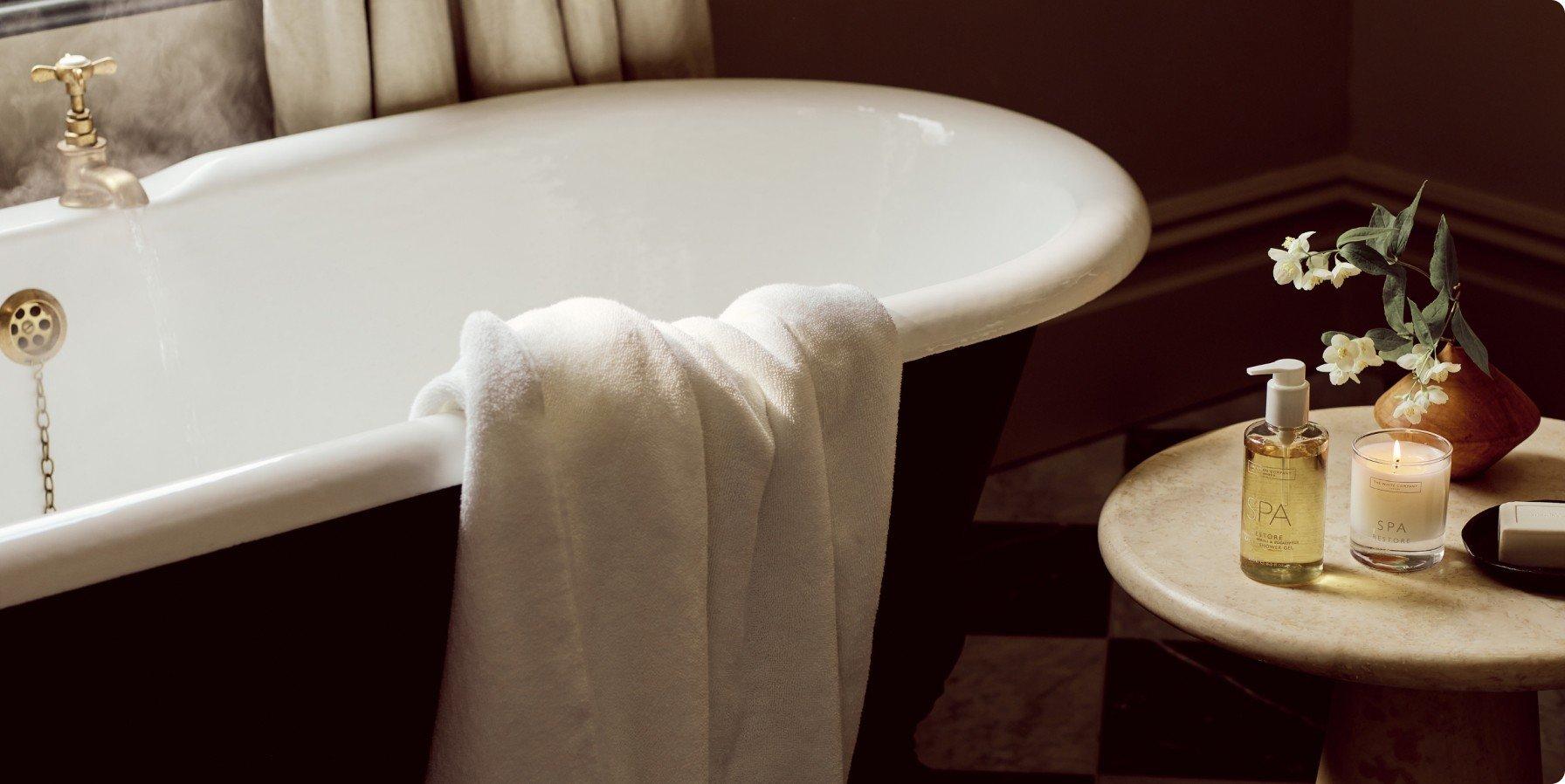 a bathtub with a candle and a vase of flowers next to it