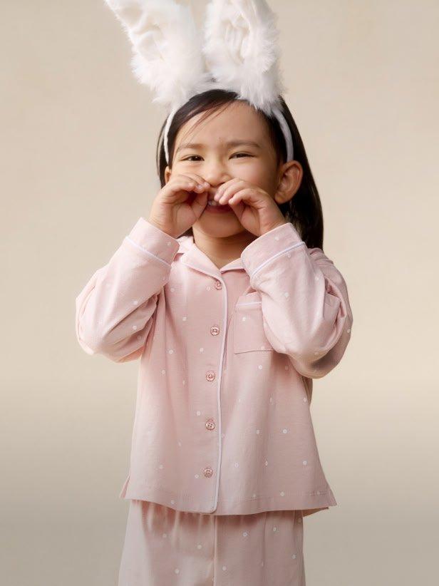 a little girl in pink pajamas with bunny ears on her head