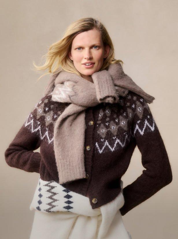 a woman in a sweater holding a gift in her hand