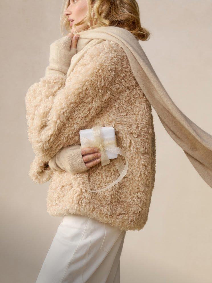a woman in a fur coat holding a gift in her hand