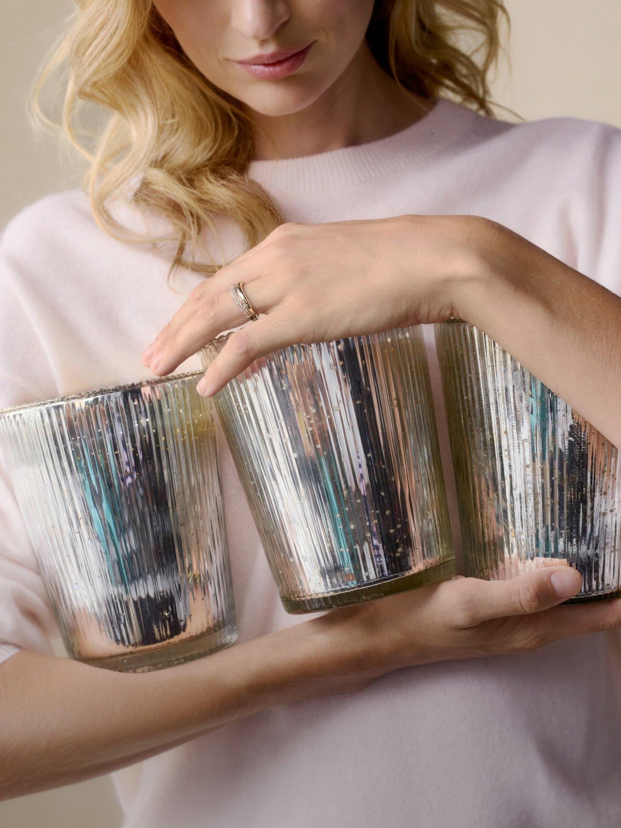 a woman holding three silver cups with a yellow sweater