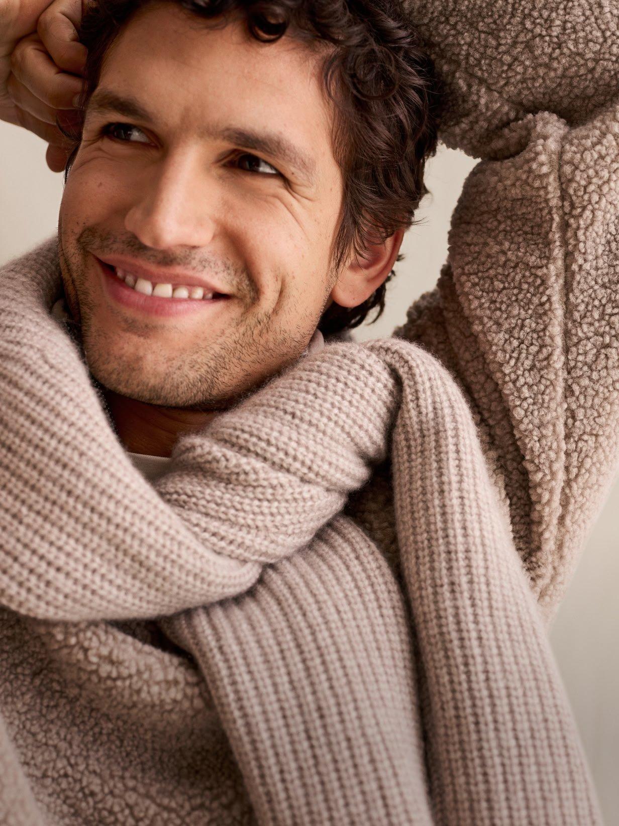 a man in a sweater holding a cup of coffee