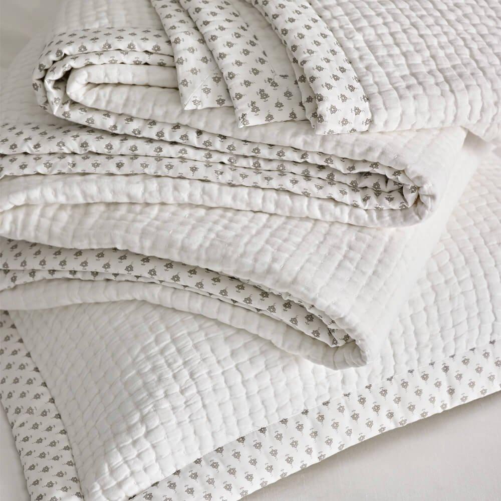 a stack of white quilts with grey dots on them