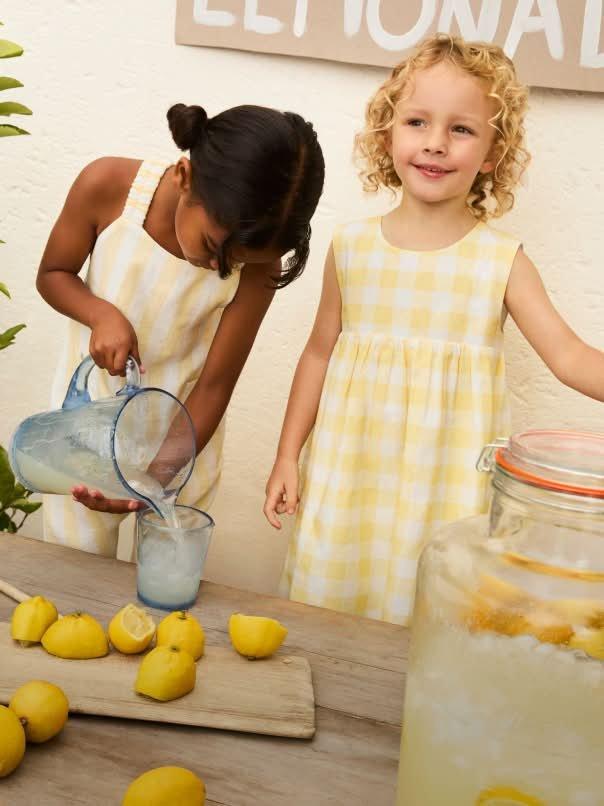 two little girls are pouring lemonade into a pitcher