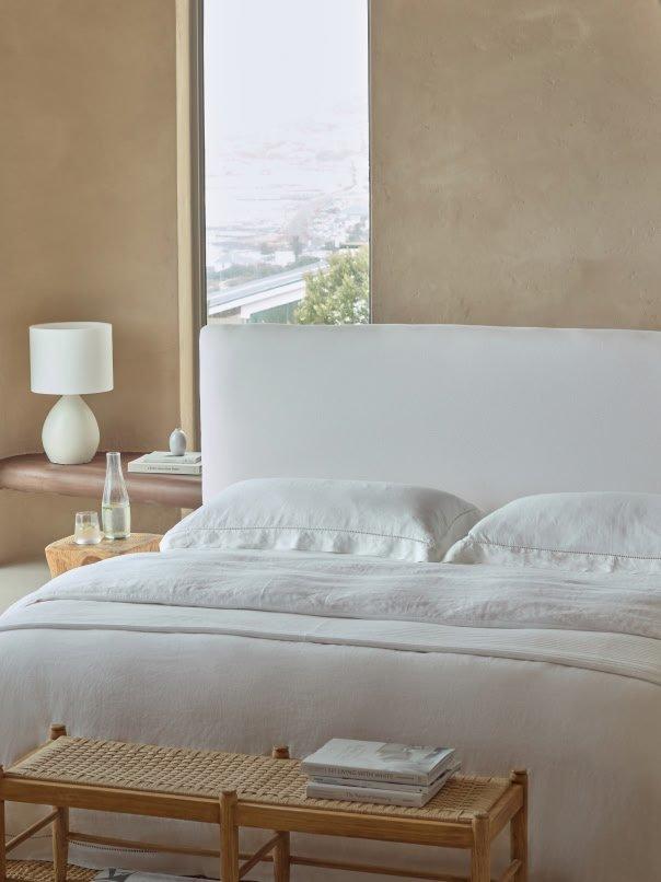 a bed with white sheets and pillows in a bedroom