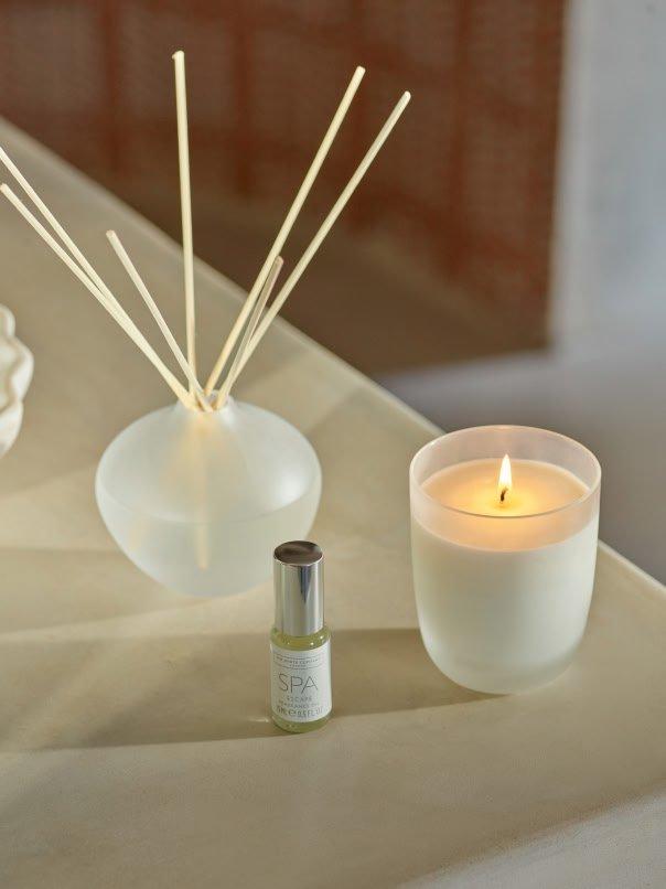 a candle, a candle holder and a bottle of perfume