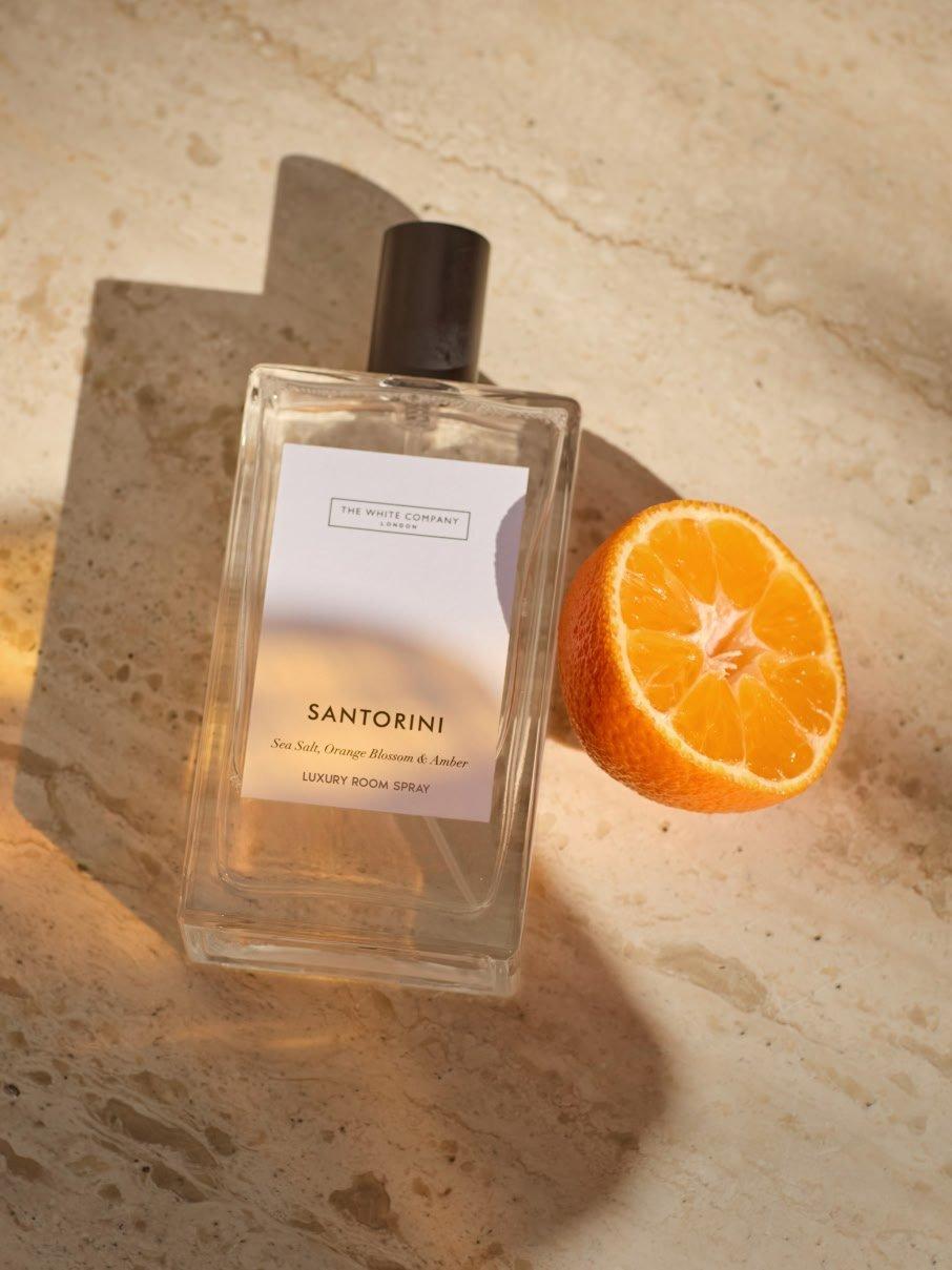a bottle of perfume next to an orange slice on a marble counter