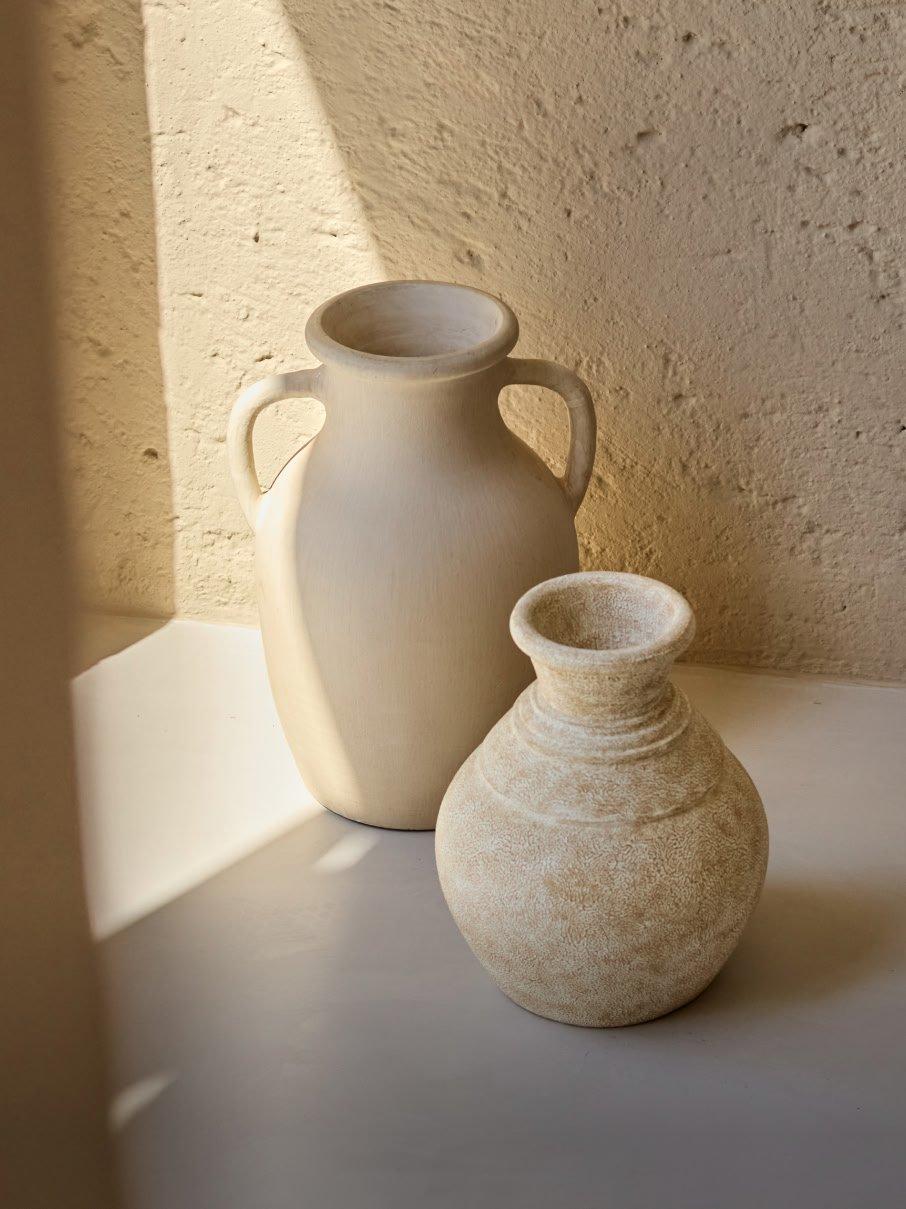 two vases sitting on a table next to each other