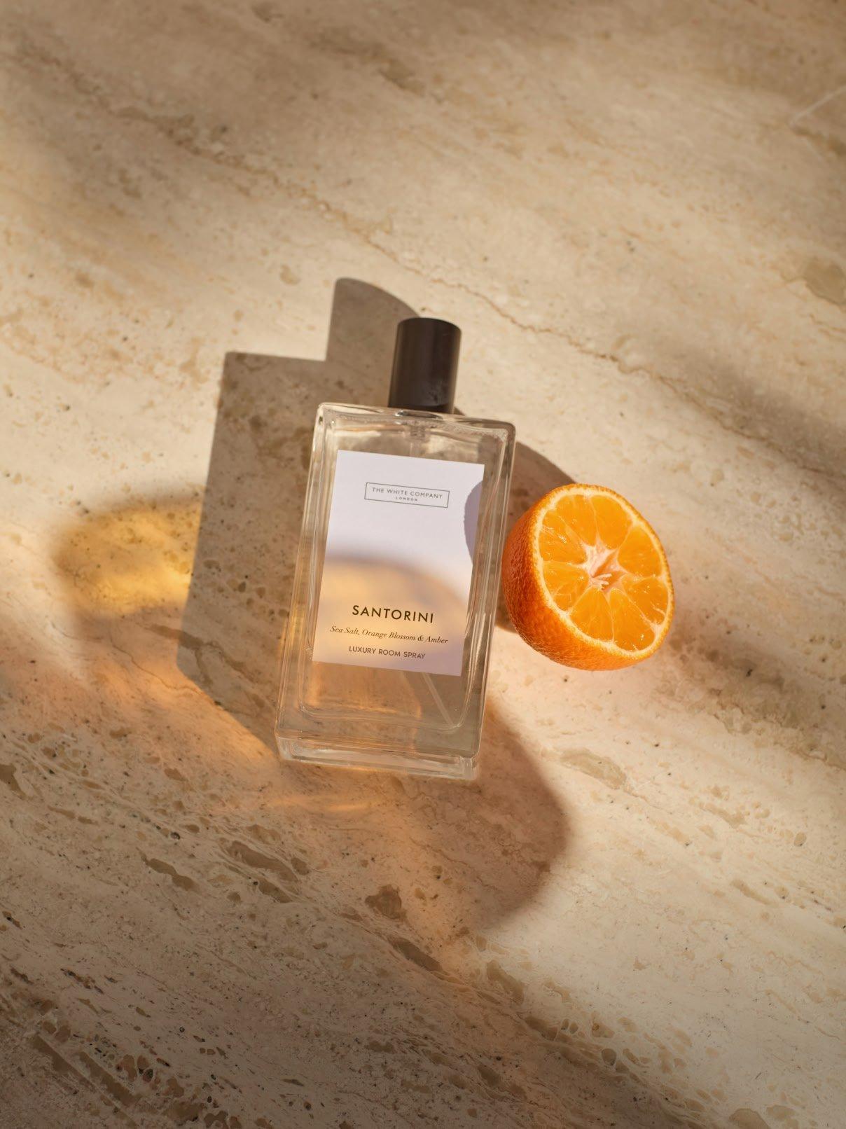 a bottle of perfume and orange slice on a table