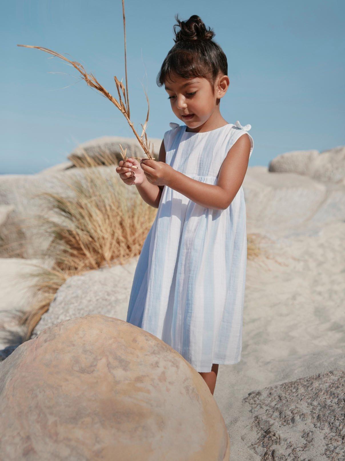 a little girl standing on a rock with a plant