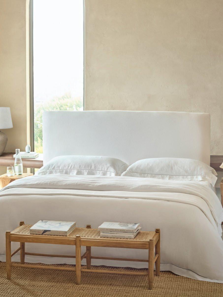 a bed with white sheets and pillows in a bedroom