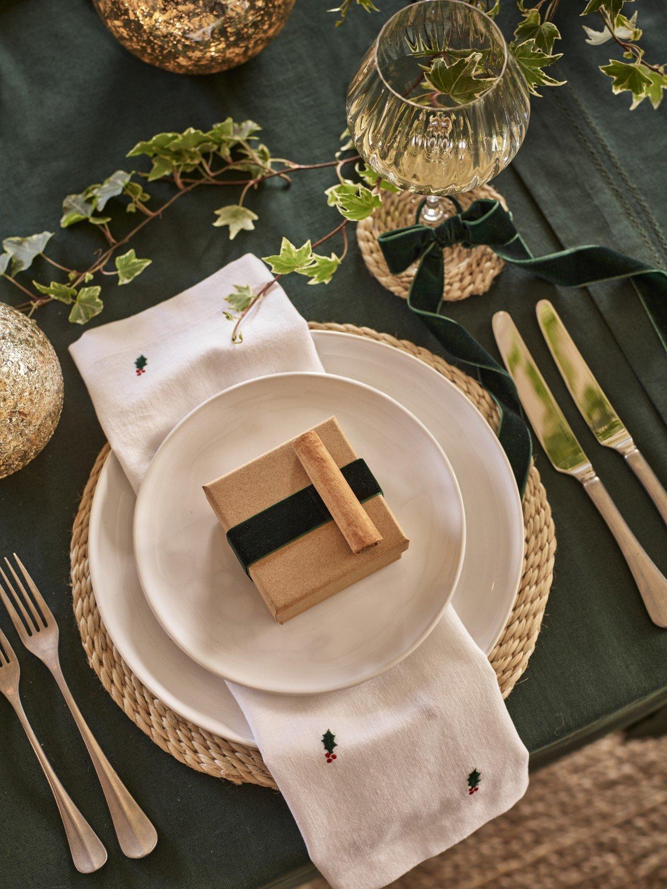 a table setting with a plate, fork, knife, napkin and a gift wrapped box