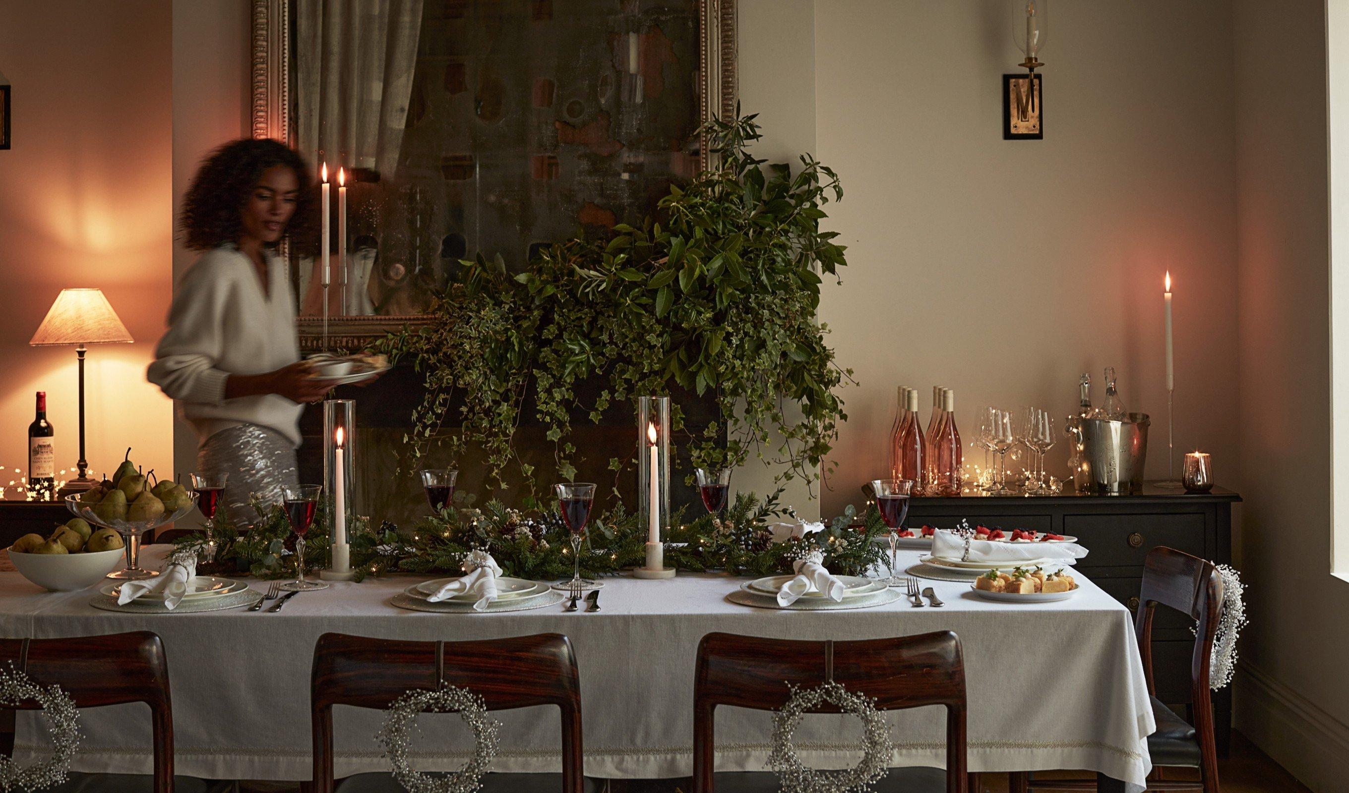 a woman standing in front of a table with a candle on it