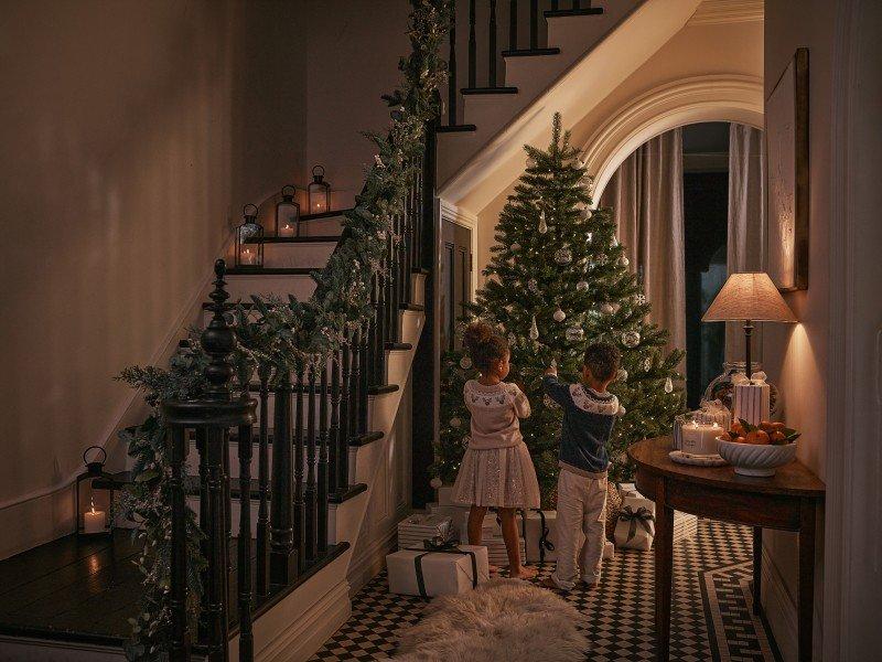 two children decorating a christmas tree in a house