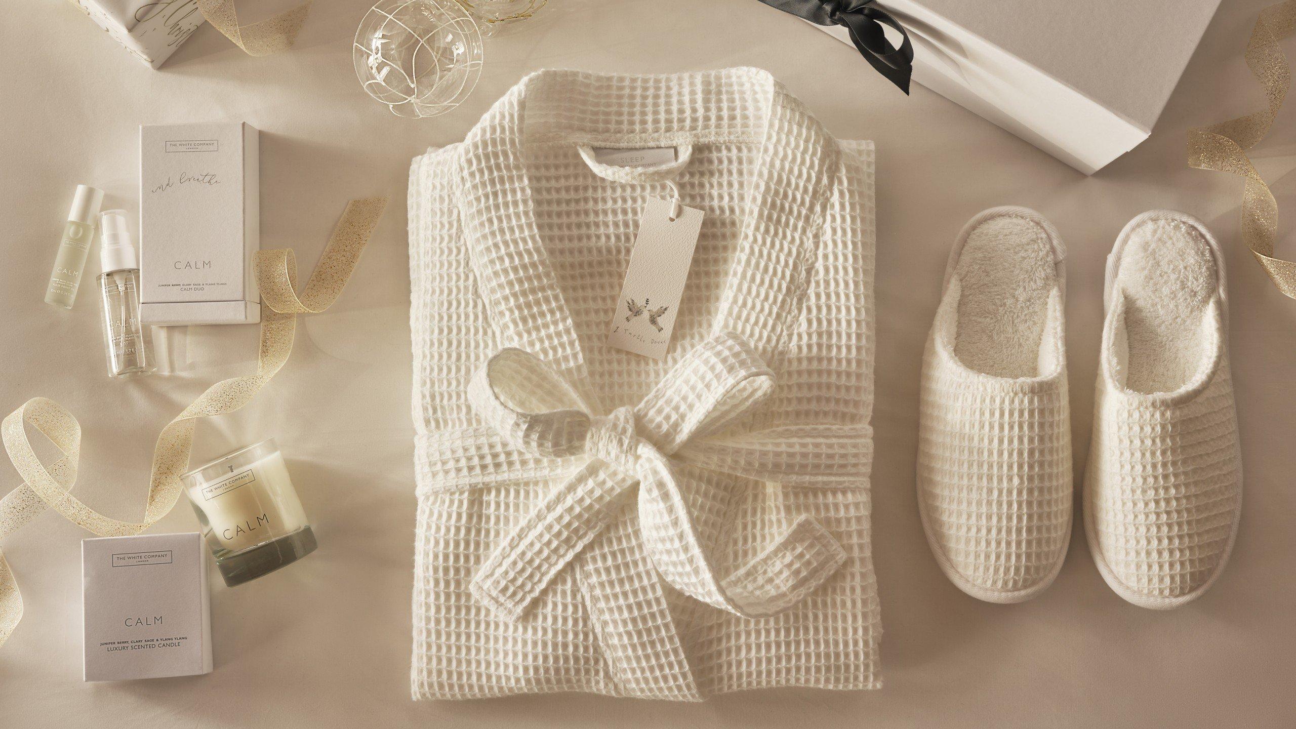 a white robe and slippers on a table with a box of chocolates