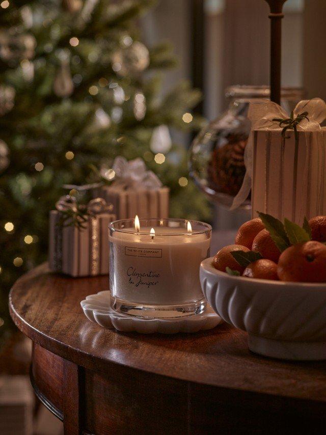 a table with a candle and a bowl of oranges on it