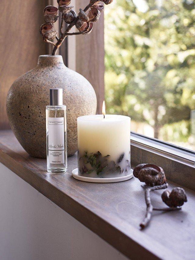 a candle and vase on a window sill with a plant