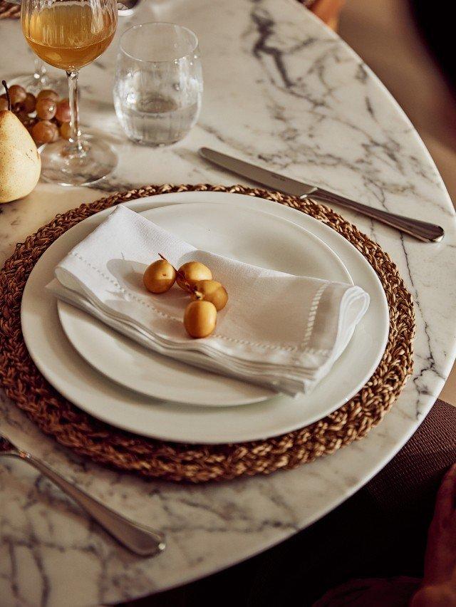 a white plate with a white napkin on it sitting on a marble table