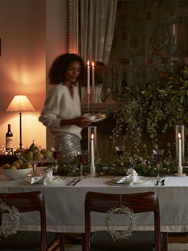 a woman standing in front of a table with candles and food