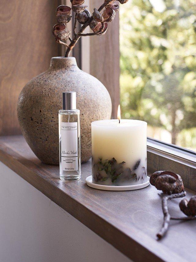 a vase with flowers and candle on window sill next to vase of dried flowers