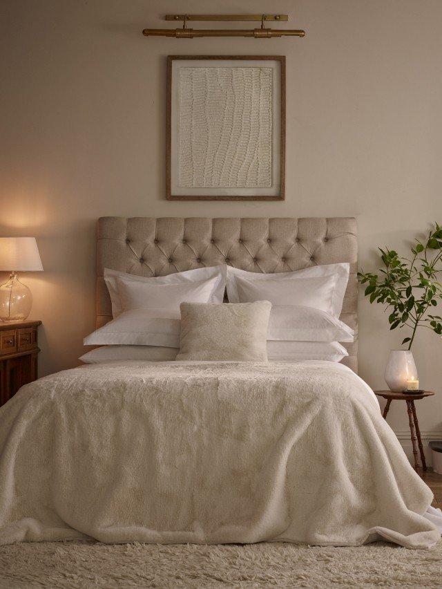 a bed with white sheets and pillows in a bedroom