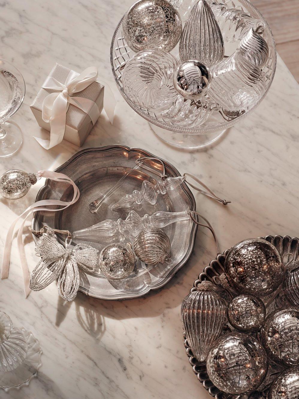 a table with silver and glass ornaments and a gift box
