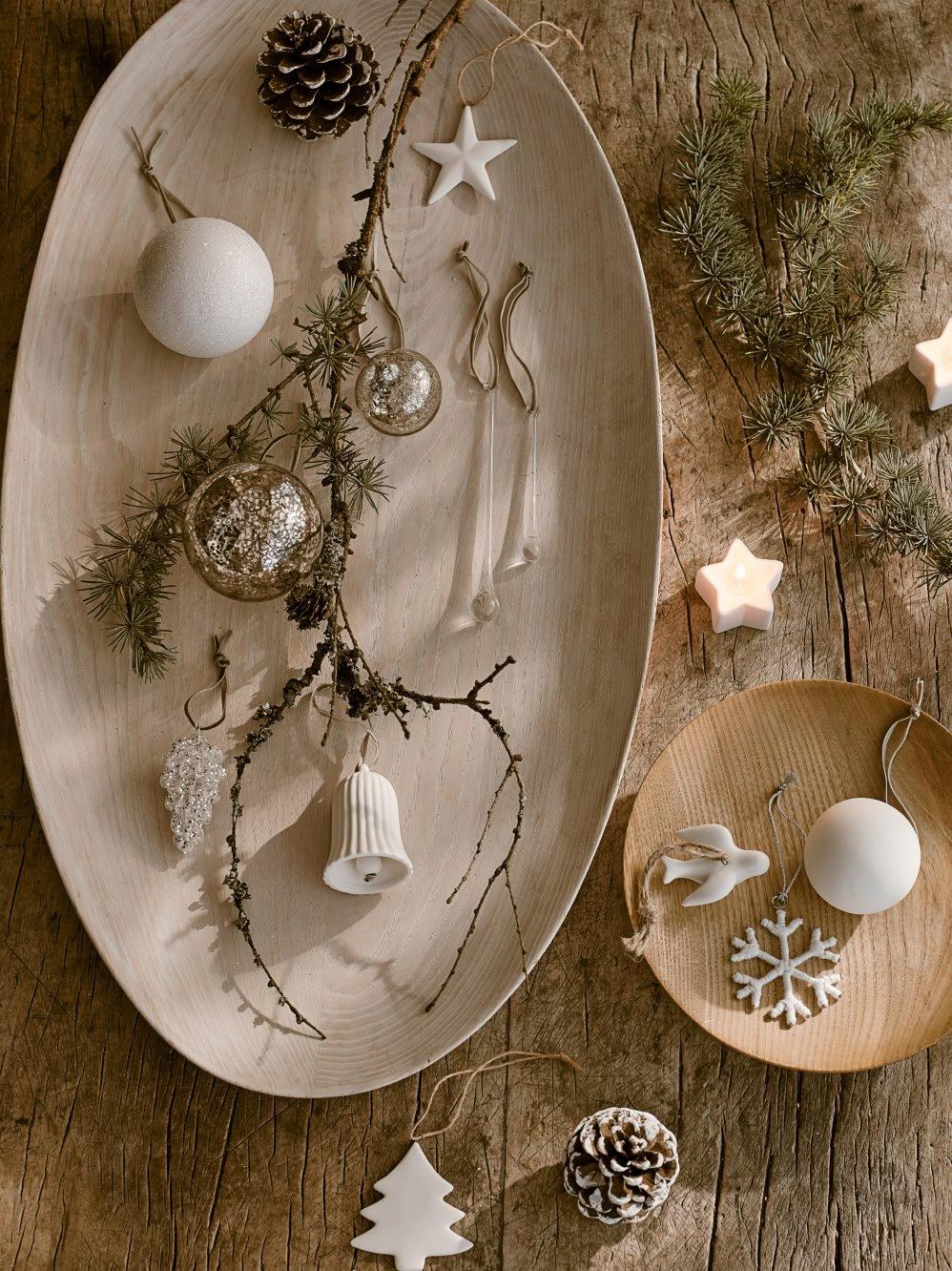 a wooden table with a plate of ornaments and a bowl of pine cones