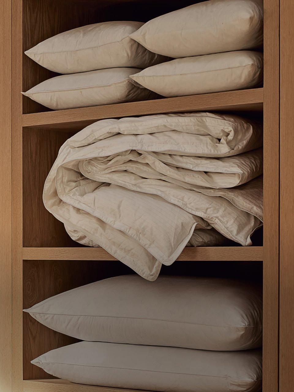 a shelf with a bunch of pillows and a blanket on it