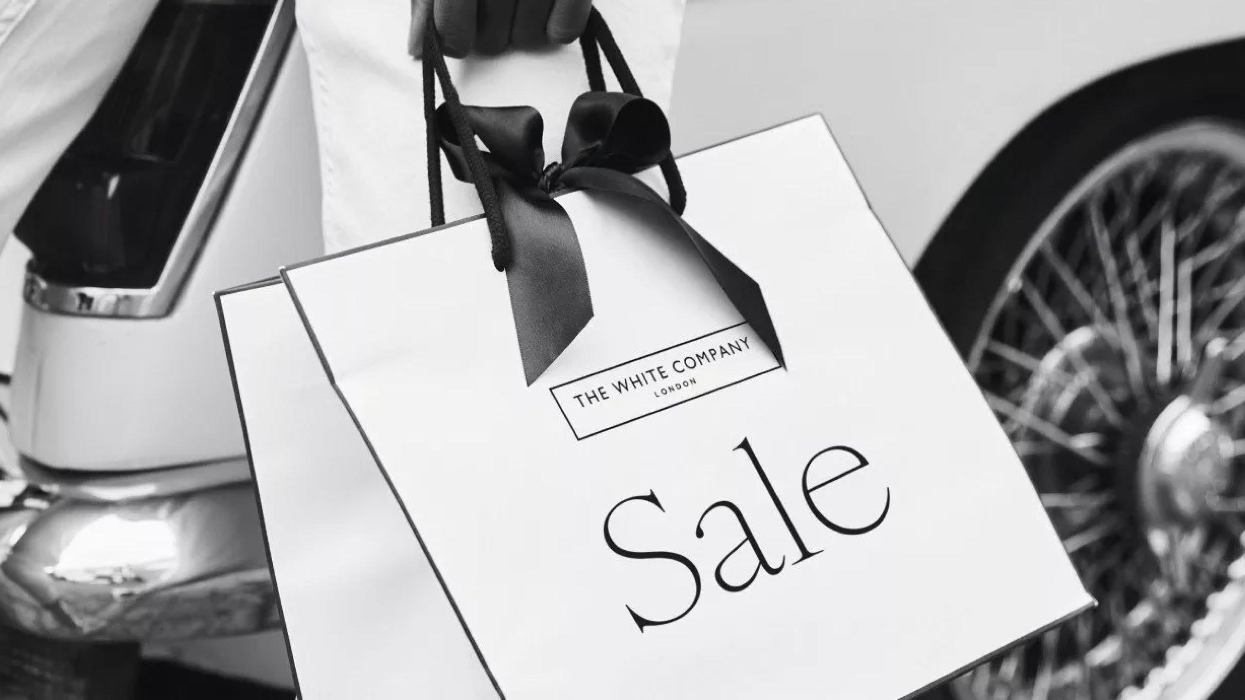 a black and white photo of a person holding a shopping bag