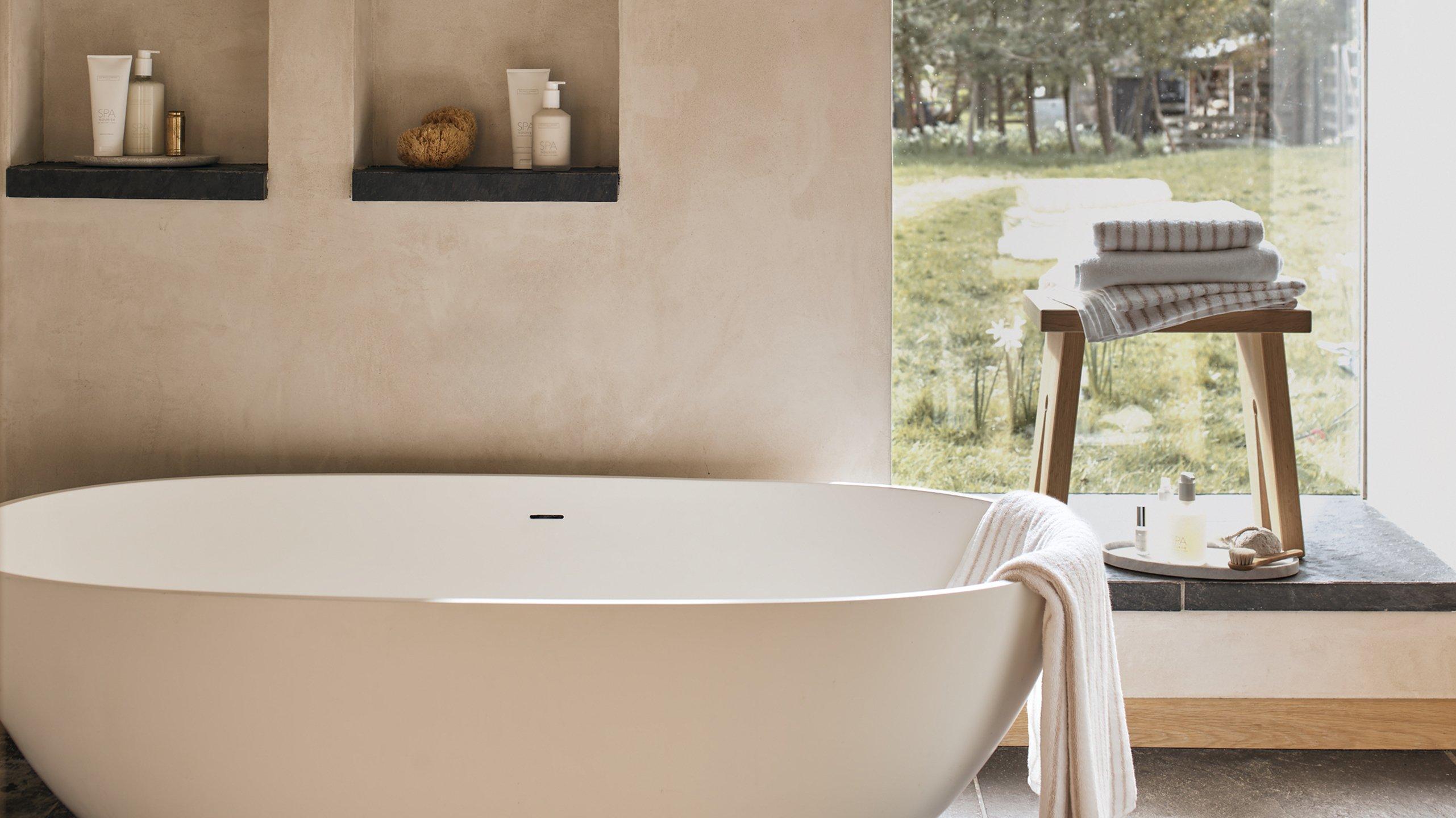 a white bath tub sitting in a bathroom next to a window