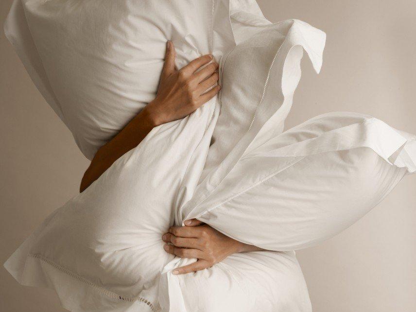 a woman sleeping in a bed with white sheets and pillows