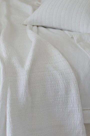 a white bed with a white comforter and pillows on it