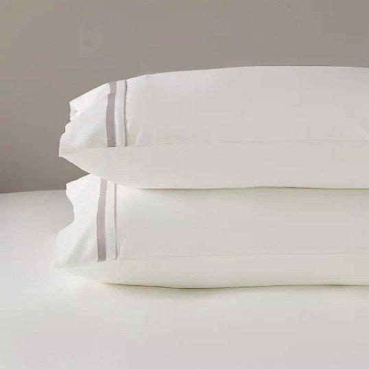 two white pillows on a bed with a white sheet