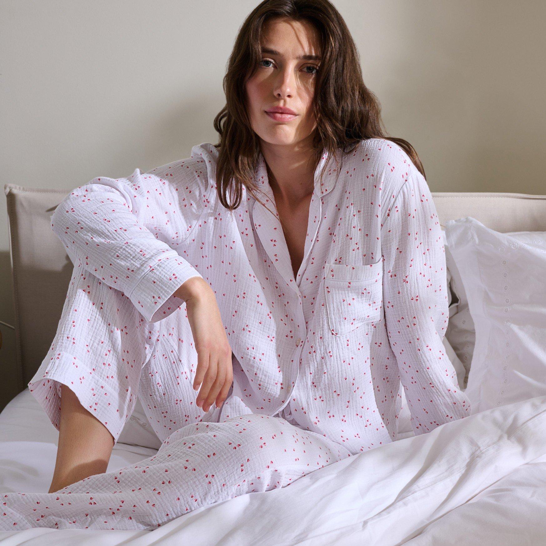 a woman sitting on a bed in a white pajama set