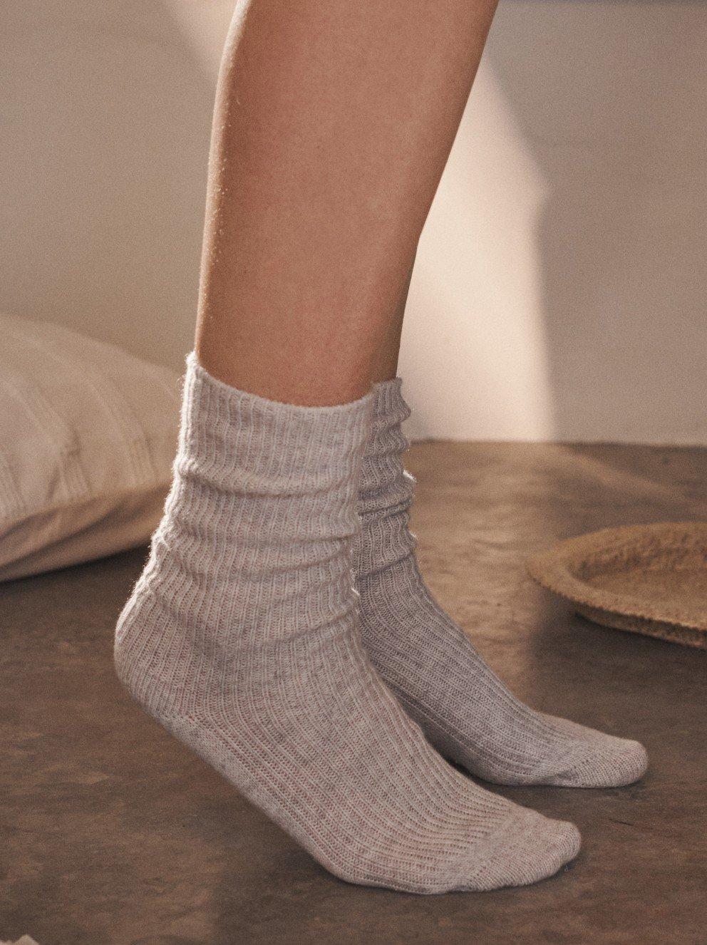 a person wearing grey socks and a white shirt on a floor
