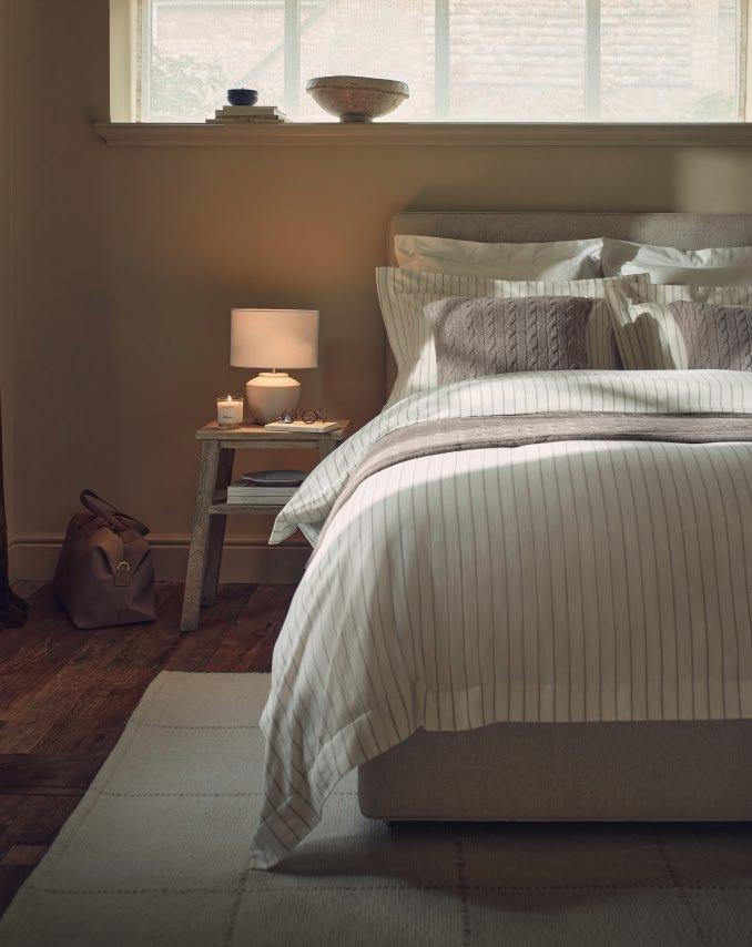 a bed with a white and gray striped comforter and pillows