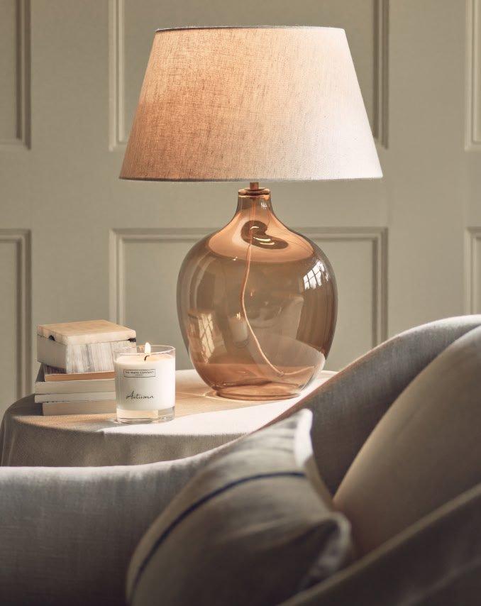 a table with a lamp and a book on it next to a chair