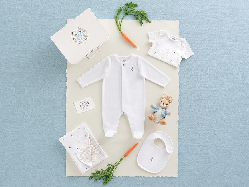 a baby's white outfit, a carrot, and a teddy bear