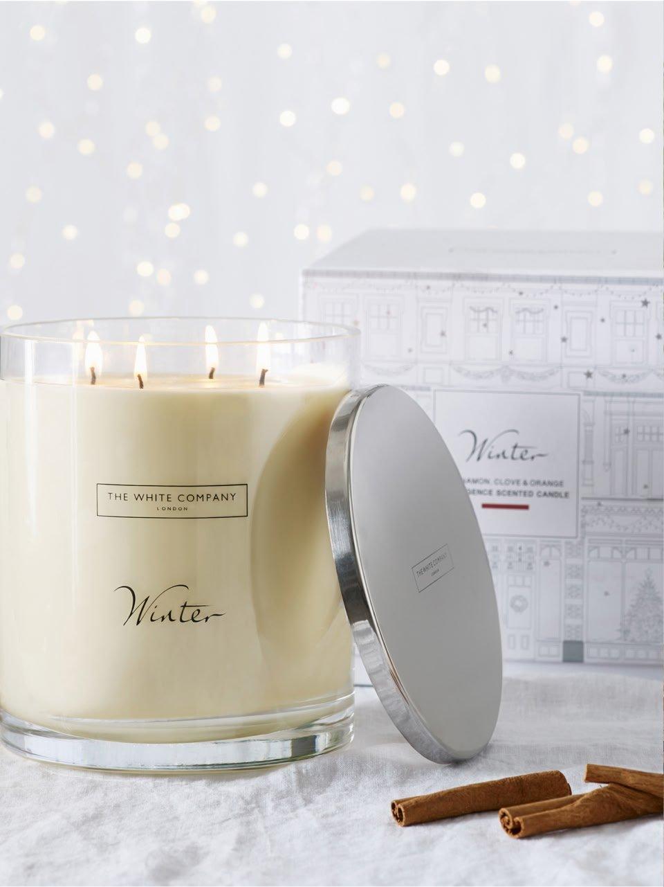a candle with a box of cinnamon sticks next to it