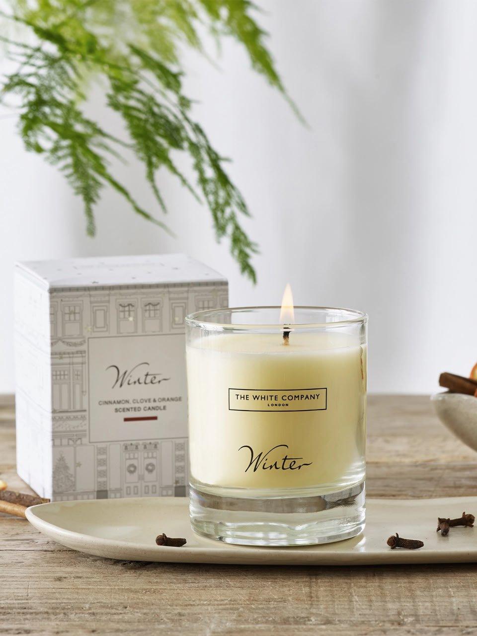 a candle on a plate next to a bowl of nuts