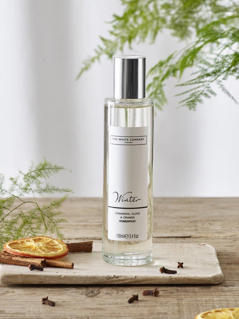 a bottle of perfume sitting on a tray next to some cinnamon sticks
