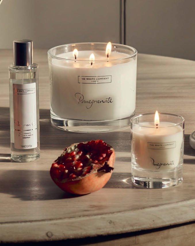 a table with a candle, a pomegranate and a bottle of perfume