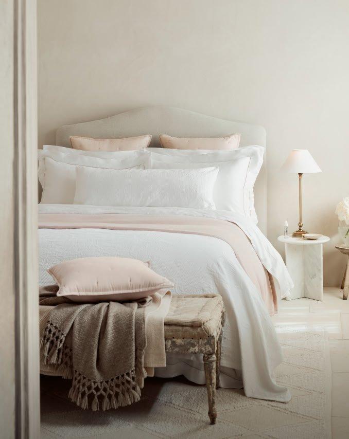 a bed with white sheets and pillows in a bedroom