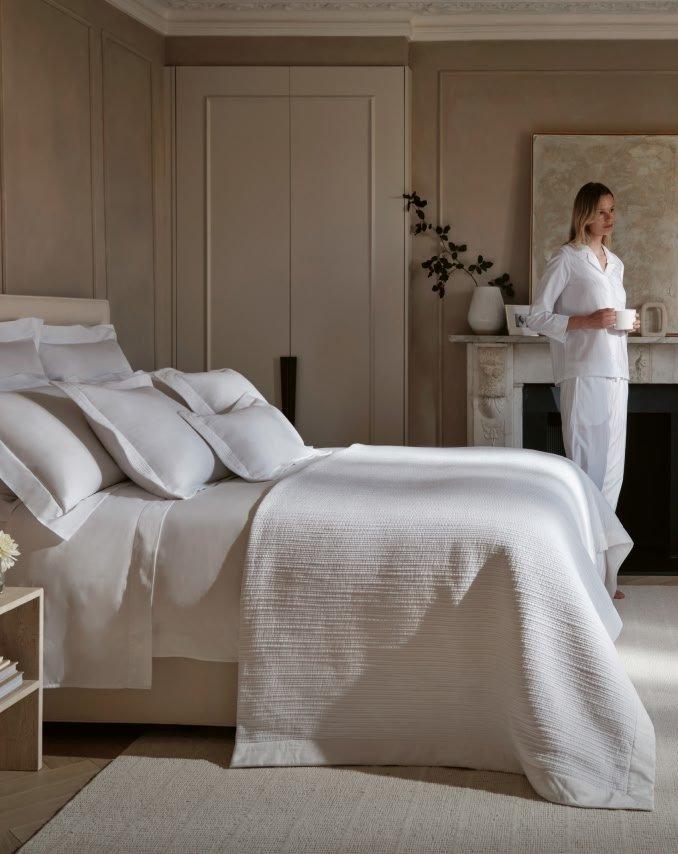 a bed with white sheets and pillows in a bedroom