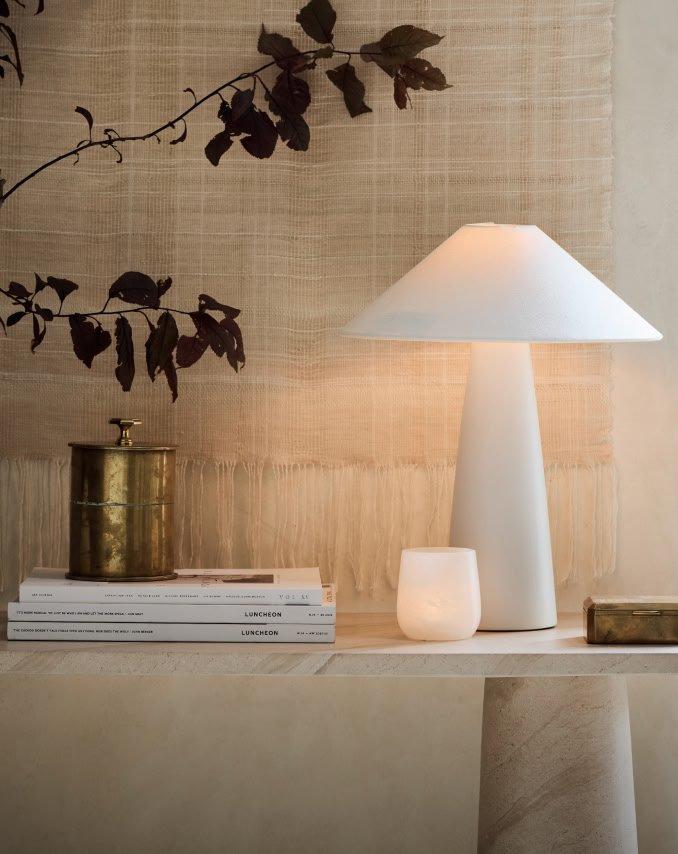 a table with a lamp and a book on it next to a chair