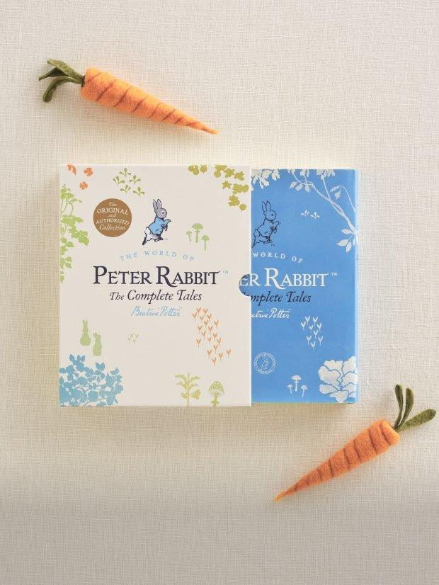 a box of peter rabbit books on a shelf next to a stuffed rabbit