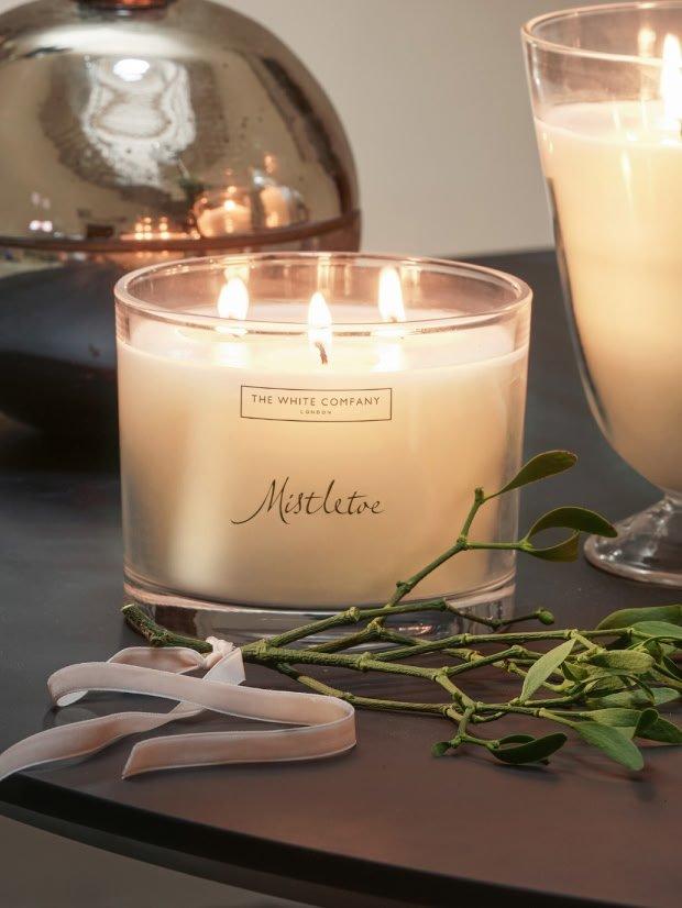 a candle and a plant sit on a table next to a vase