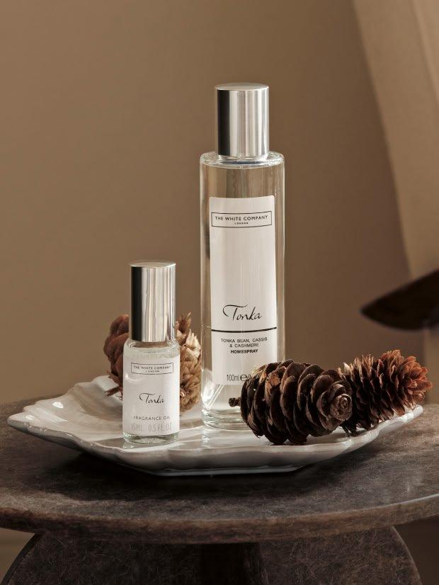 a couple of bottles of perfume sit on a plate with pine cones