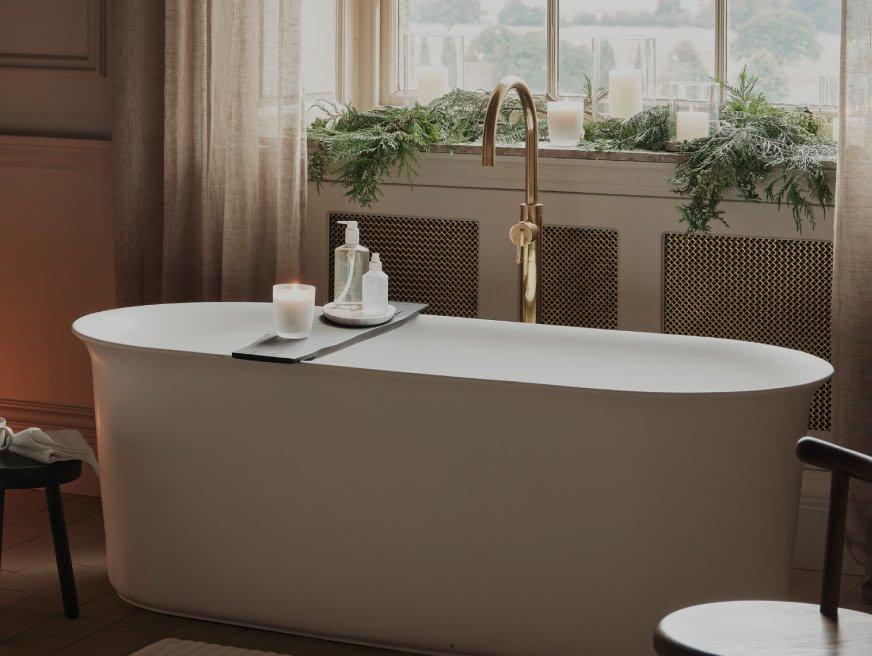a bathtub sitting in a room with a window and a candle