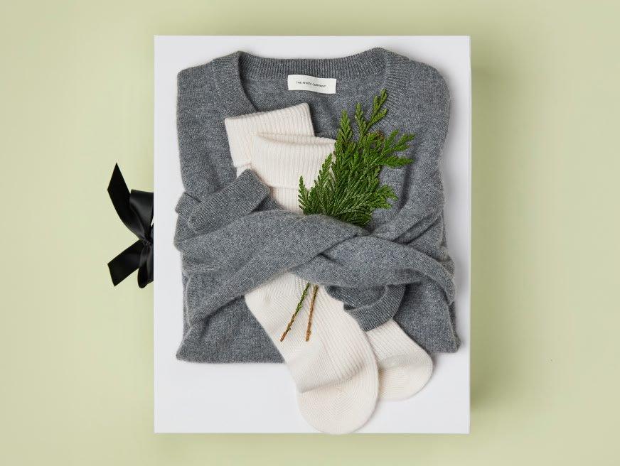 a grey sweater with a sprig of evergreen in it